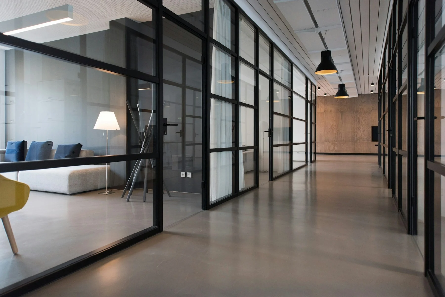 Clean commercial office corridor with glass partitions and natural light