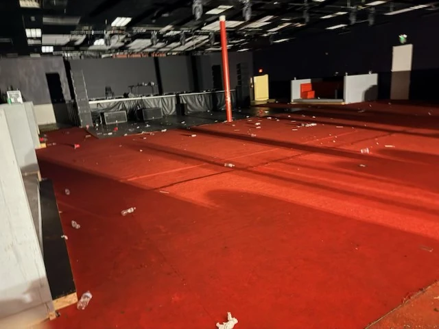 Red-carpeted event floor with post-event debris