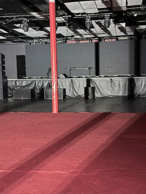 Stage front and adjoining red-carpeted floor after cleanup